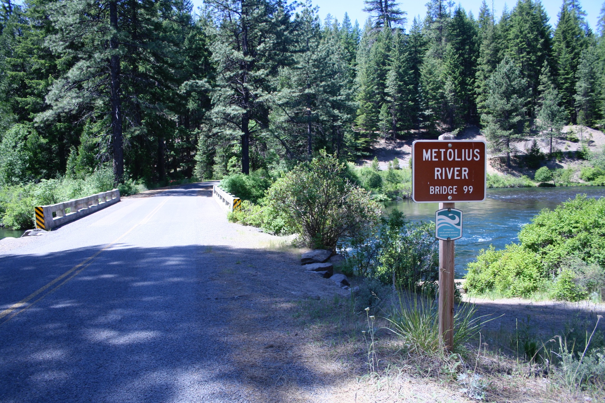 Bridge 99 crossing the Metolius River beside a sign reading Metolius River Bridge 99
